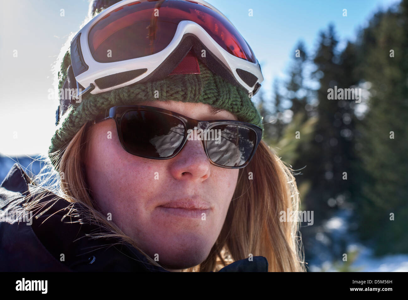 Junge Frau, die in die Kamera, Sonnenbrille und einen Ski-Hut mit Brille  auf dem Kopf tragen Stockfotografie - Alamy