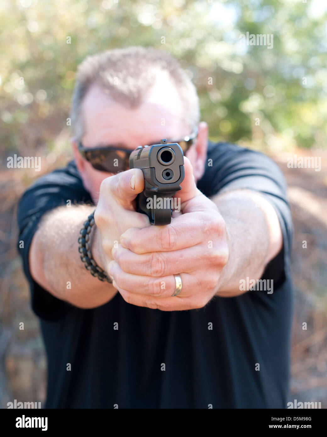 Weißer Mann, mit dem Ziel, einer Pistole im stehen in die gleichschenklig Position bei voller Streckung im kinästhetischen Ausrichtung Stockfoto