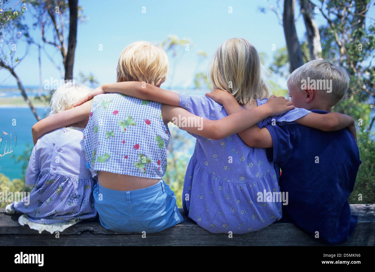 Familie, Kinder, 4 Kinder (3 Mädchen/1 Junge) hintereinander halten Schultern, Rückansicht, blonde Haare von 2-8 Jahre alt. Stockfoto