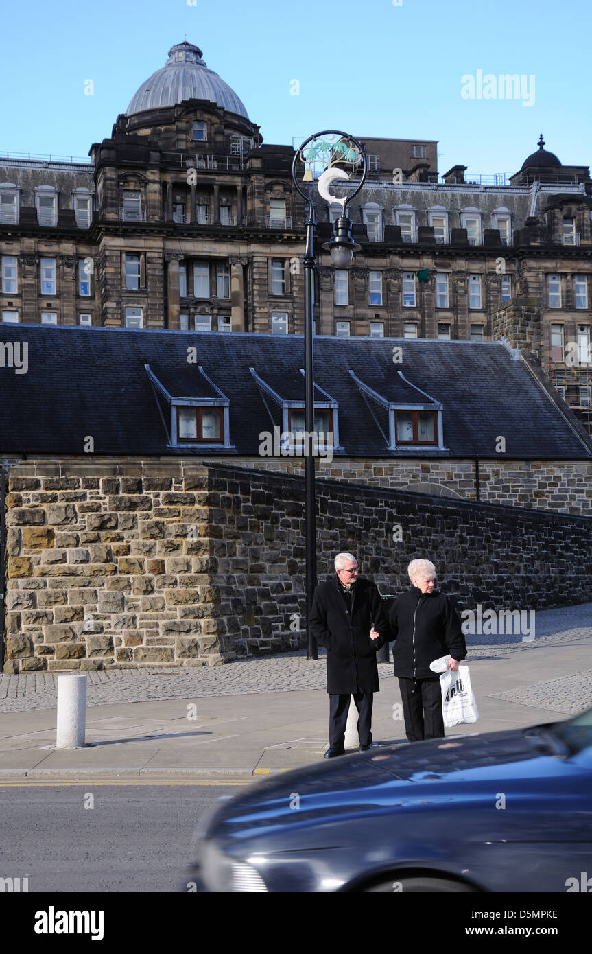 Ältere Paare warten, stark befahrene Straße in Glasgow, Scotland, UK zu überqueren Stockfoto