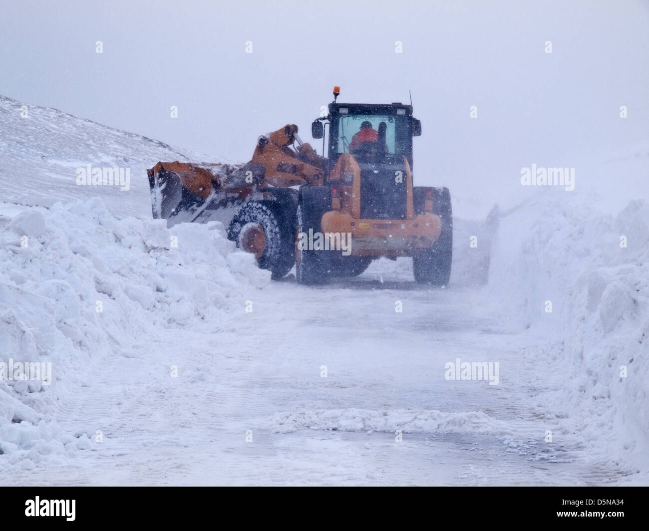 Ein Traktor / Bagger versucht, eine Straße Peak District zu halten öffnen Sie in starkem Schneefall im Winter 2013 Stockfoto