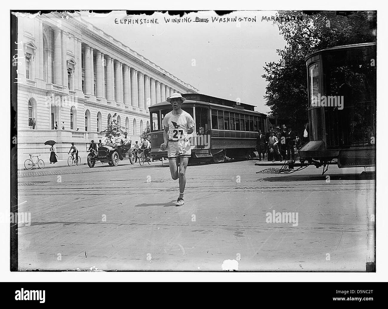 Dieses Foto zeigt Elphinstone, der den Washington Marathon in den 1910er Jahren gewann, und die Straßen und Autos der Stadt sind im Hintergrund zu sehen. Der Marathon war Teil der amerikanischen Leichtathletikveranstaltungen des frühen 20. Jahrhunderts. Stockfoto
