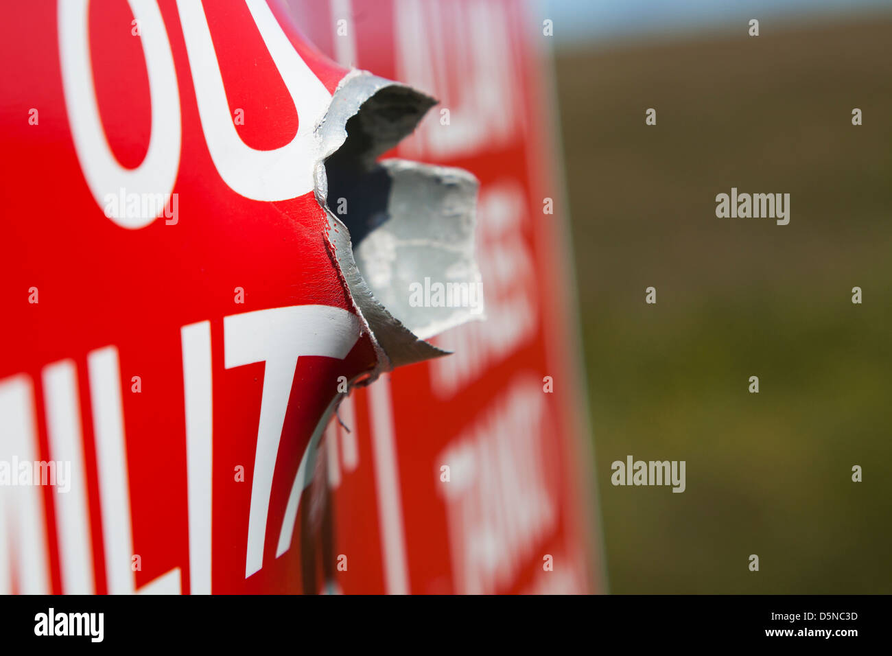 Einschussloch durch ein Metall-Schild, Castlemartin Palette, Pembrokeshire Stockfoto