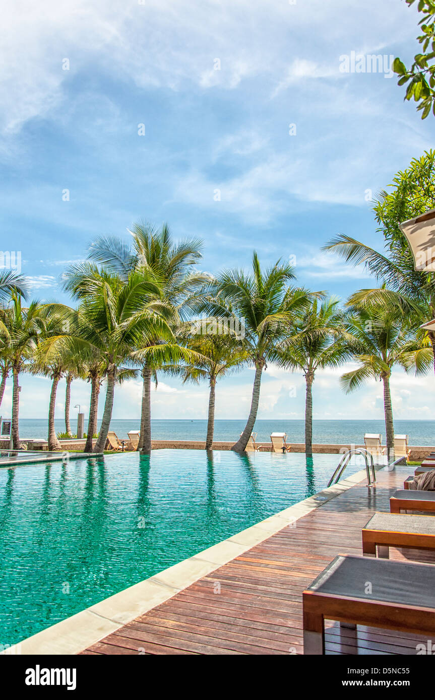 Ein Infinity-Hotelpool in Thailand mit einer Paradies-Kulisse von Palmen und das Meer. Stockfoto