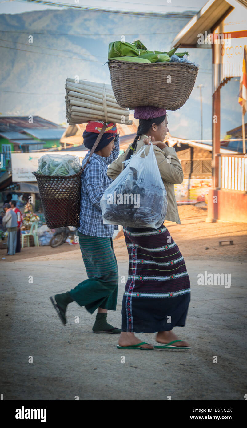 In Myanmar tragen Frauen schwere Lasten auf ihren Köpfen während des Tragens des traditionellen "Htamein"-Rocks. Stockfoto