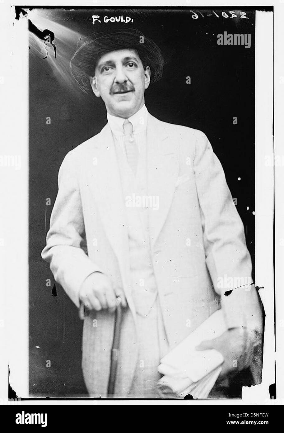 Dieses Foto zeigt Frank J. Gould, eine prominente Persönlichkeit in der amerikanischen Politik und Wirtschaft des frühen 20. Jahrhunderts. Er ist hier in einem weißen Anzug mit grauem Hut zu sehen. Stockfoto