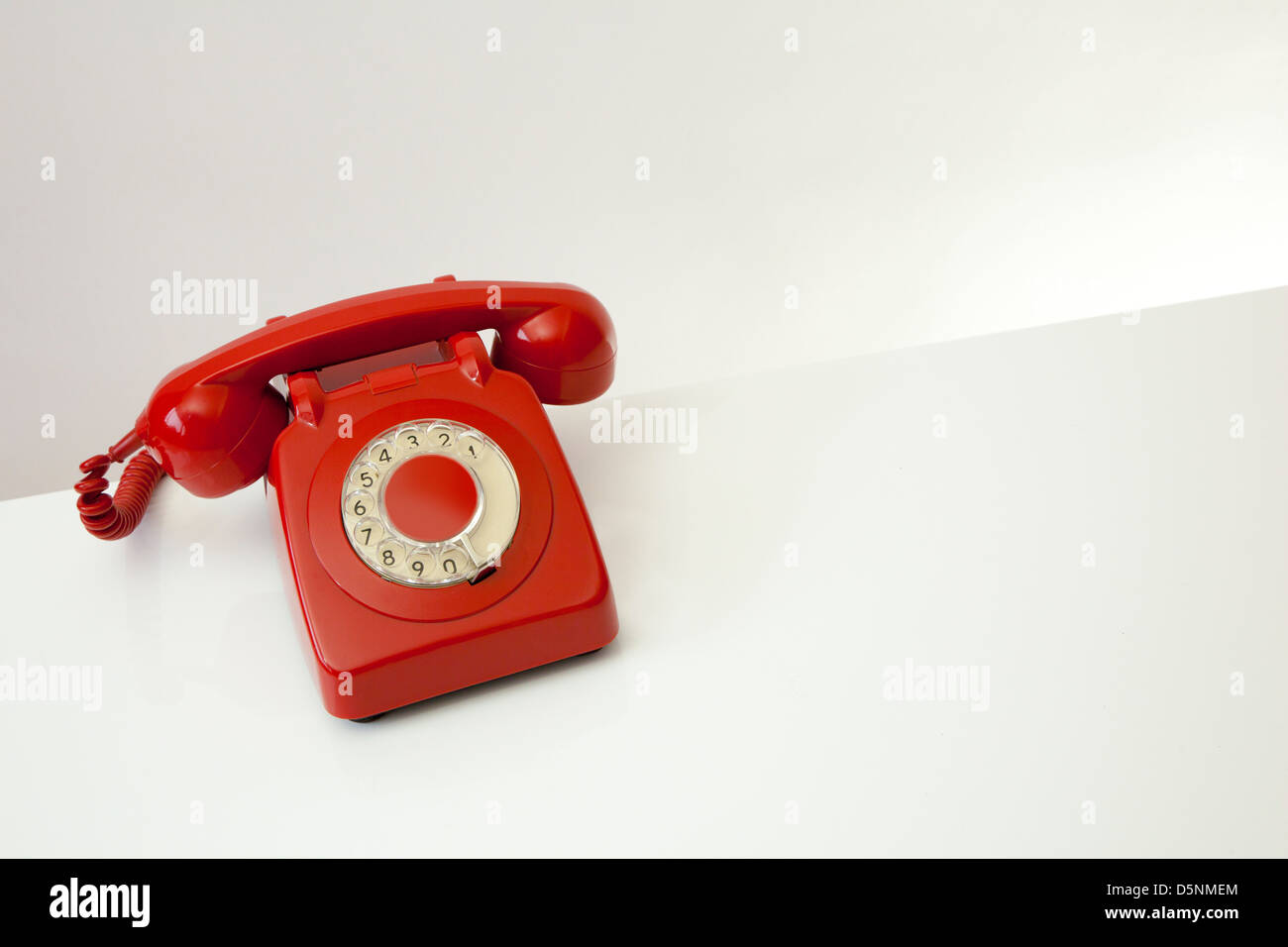 Rote Retro-Stil Telefon auf einen leichten grau / weißen Tischfläche, weiß/grau Hintergrund mit Platz für Text. Stockfoto