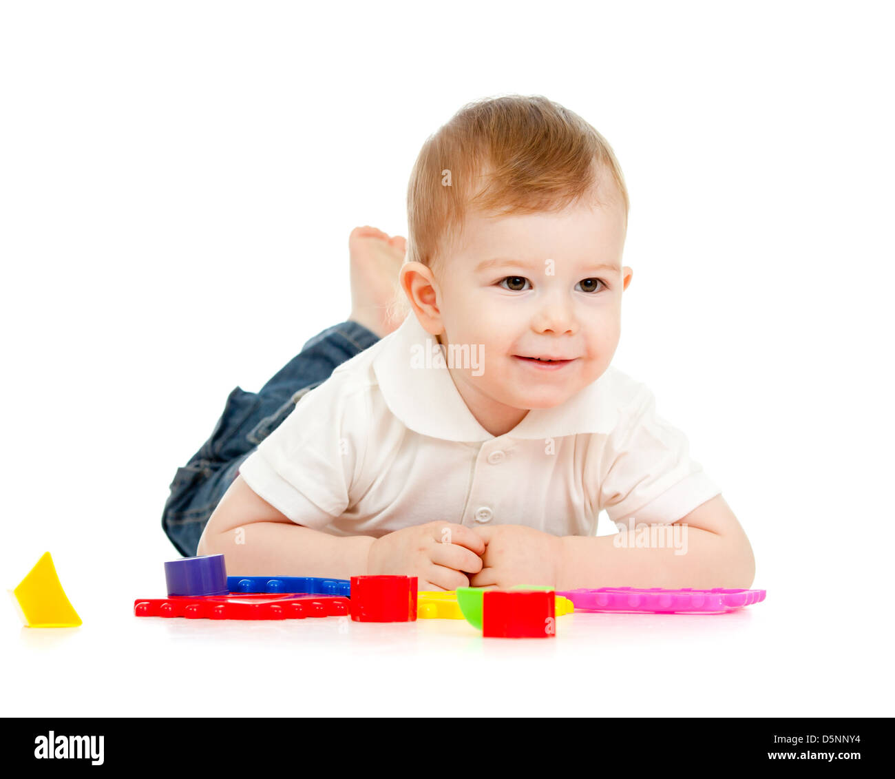 Nettes kleines Kind spielt mit Spielzeug auf Boden, liegend, isoliert auf weiß Stockfoto
