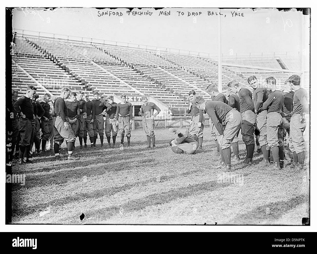 Dieses Foto aus dem frühen 20. Jahrhundert zeigt einen Trainer namens Sanford, der Männern beibringt, wie man den Ball während des Fußballtrainings an der Yale, einer Ivy League Universität, fallen lässt. Stockfoto