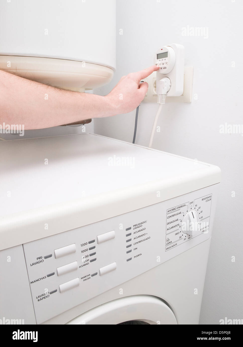 Timer zur Energieeinsparung für die Warmwasserbereitung und eine Person, die Programmierung. Das Foto zeigt auch eine Unterlegscheibe Stockfoto