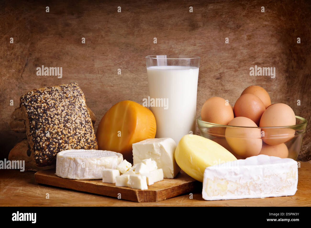 Stillleben mit Milchprodukten, Milch, Eiern, Brot und Käse auf einem Vintage Holz-Hintergrund Stockfoto