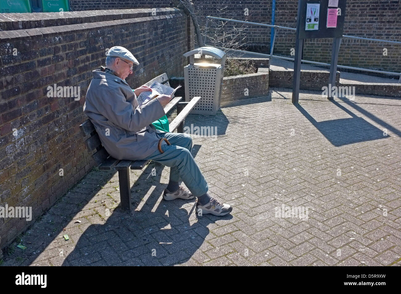 Ein Alter Mann auf einer Bank zu lesen. Stockfoto