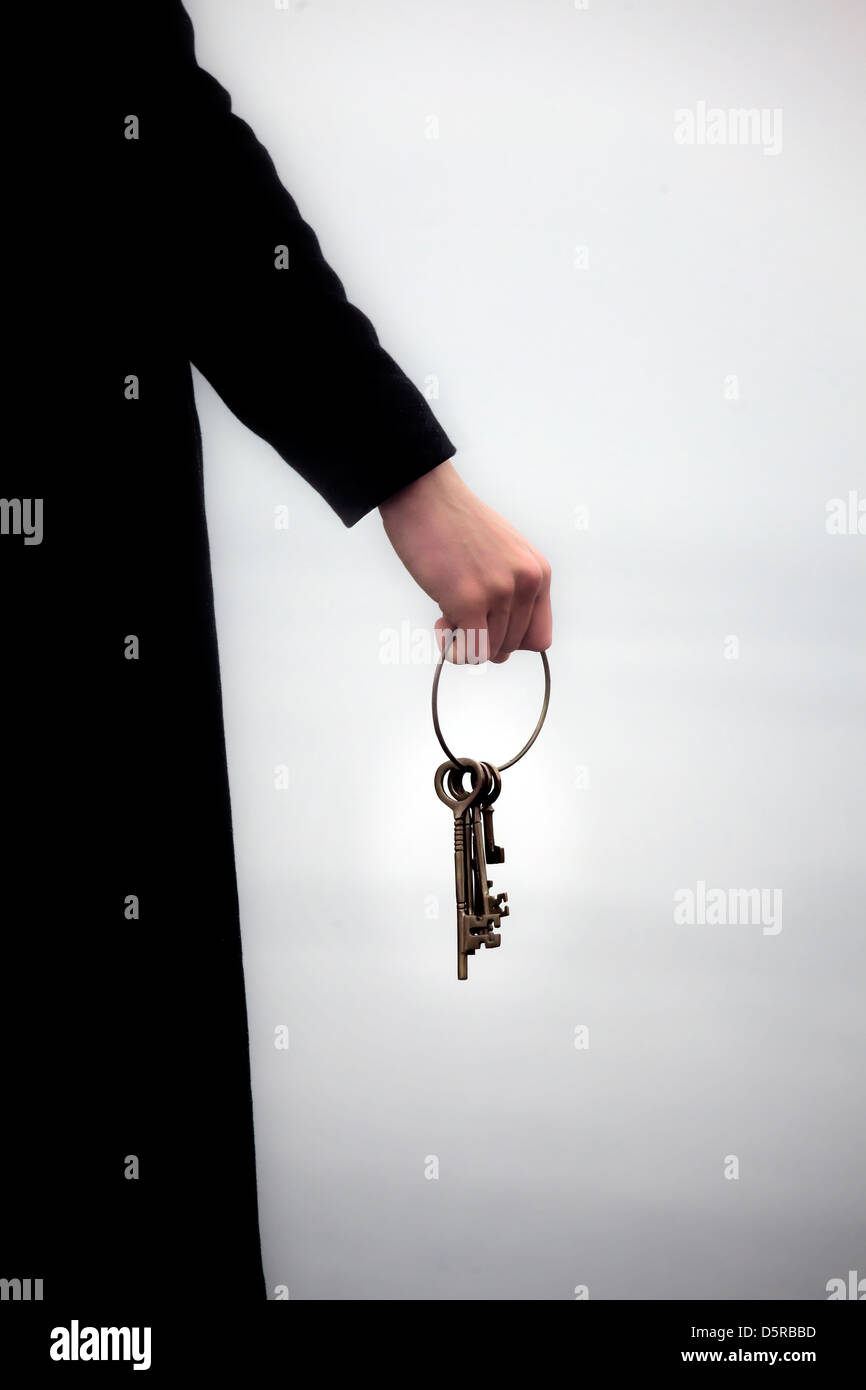 ein Mann in einem schwarzen Mantel hält einen Schlüsselring mit alten Schlüsseln Stockfoto