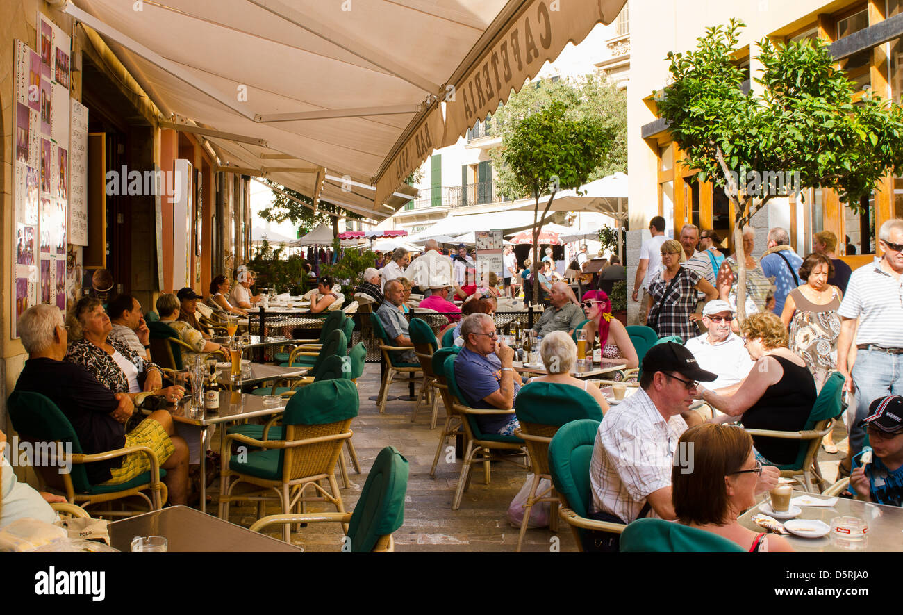Urlauber genießen ein al fresco Mittagessen im Freien eine Café-Bar in der Altstadt von Alcudia, Mallorca, Spanien. Stockfoto