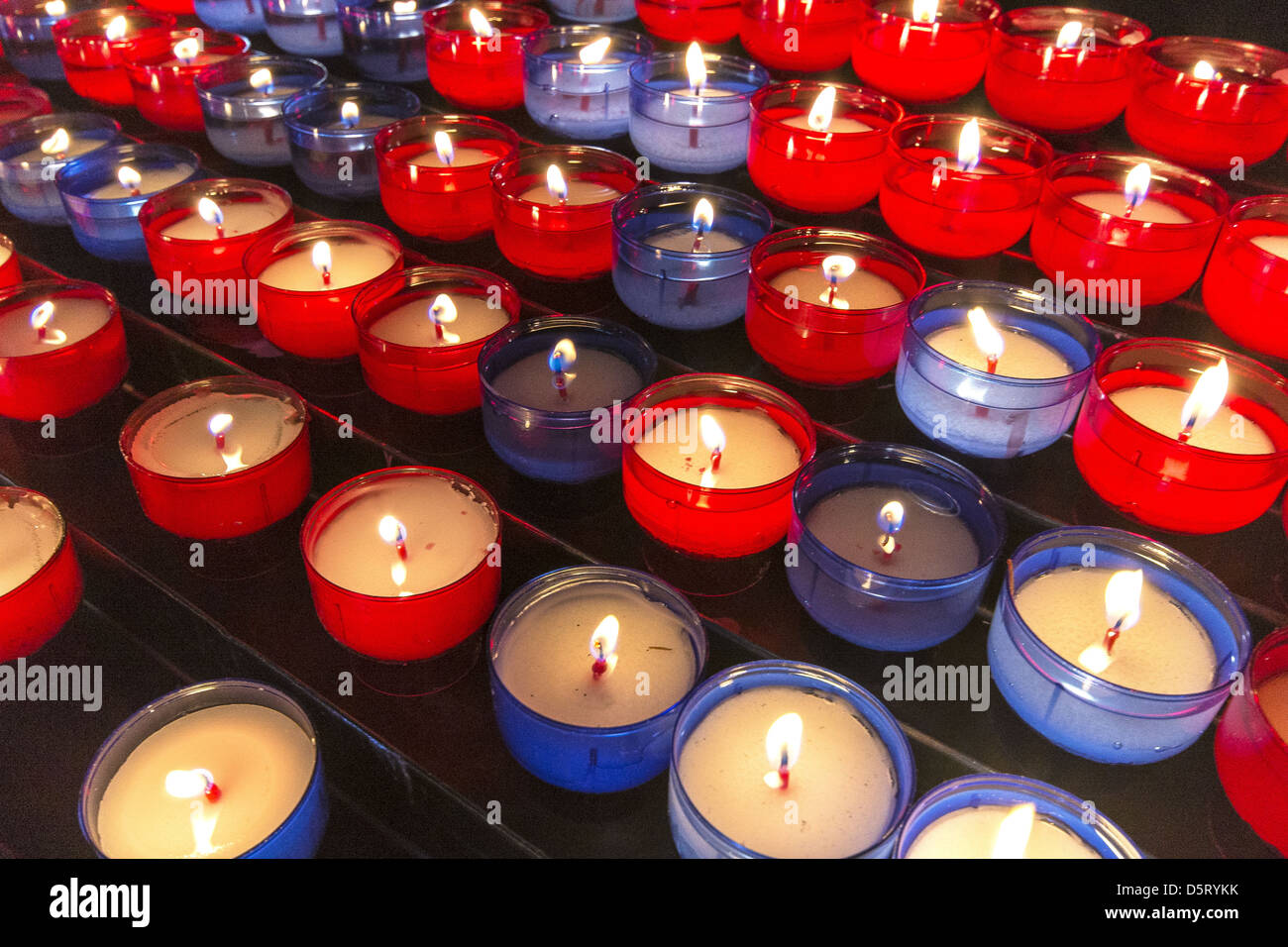 Reihen von roten und blauen Kerzen Display auf eine Kirche Kerzenständer Stockfoto