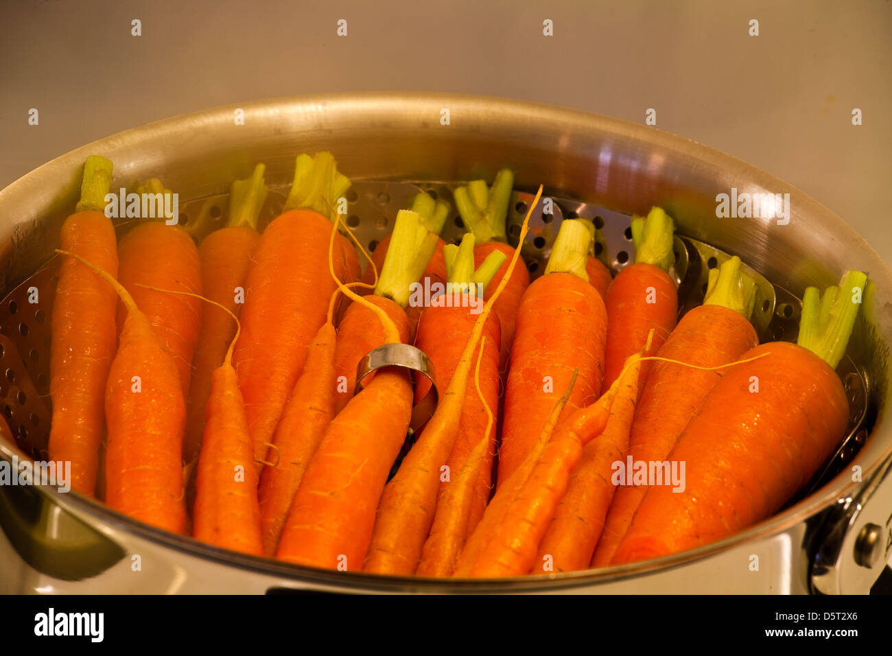 Karotten Kochen in einem Dämpfeinsatz Stockfoto