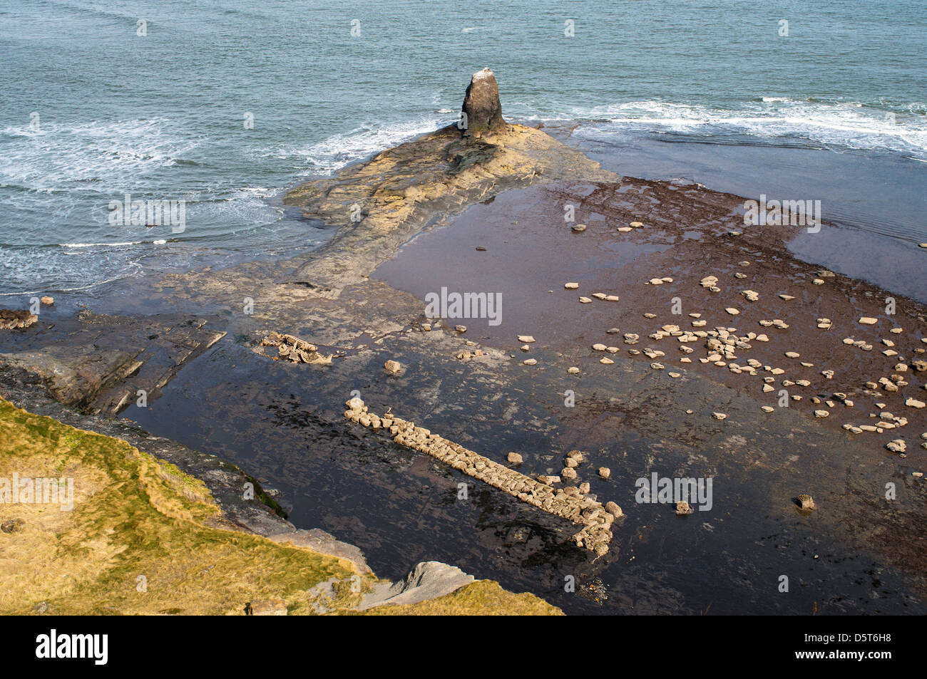 Schwarzer NAB-Felsen mit Überresten von Hafen und Schiffswrack aus dem 17.. Jahrhundert in Saltwick Bay in der Nähe von Whitby, North Yorkshire, England, Großbritannien Stockfoto