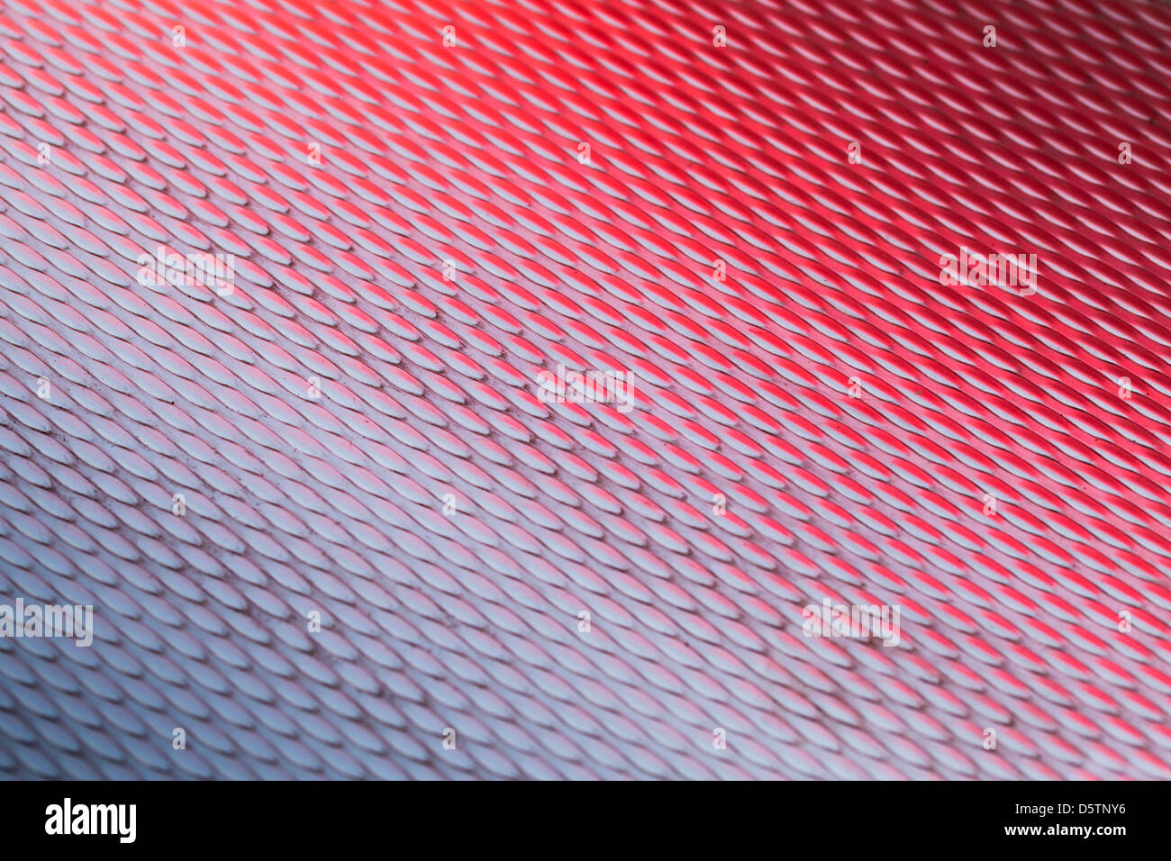 Metalloberfläche mit Diamant-Muster und roten Reflexionen Stockfoto