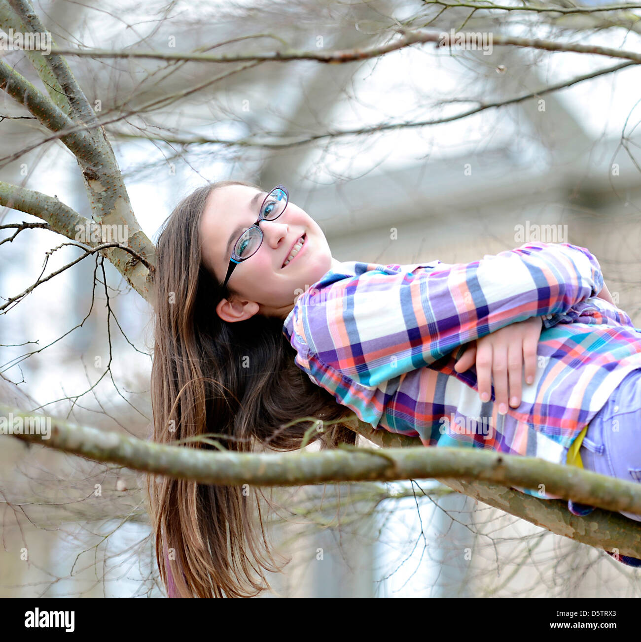 Eine schöne Teenager-Mädchen auf den Ästen eines Baumes liegen. Stockfoto