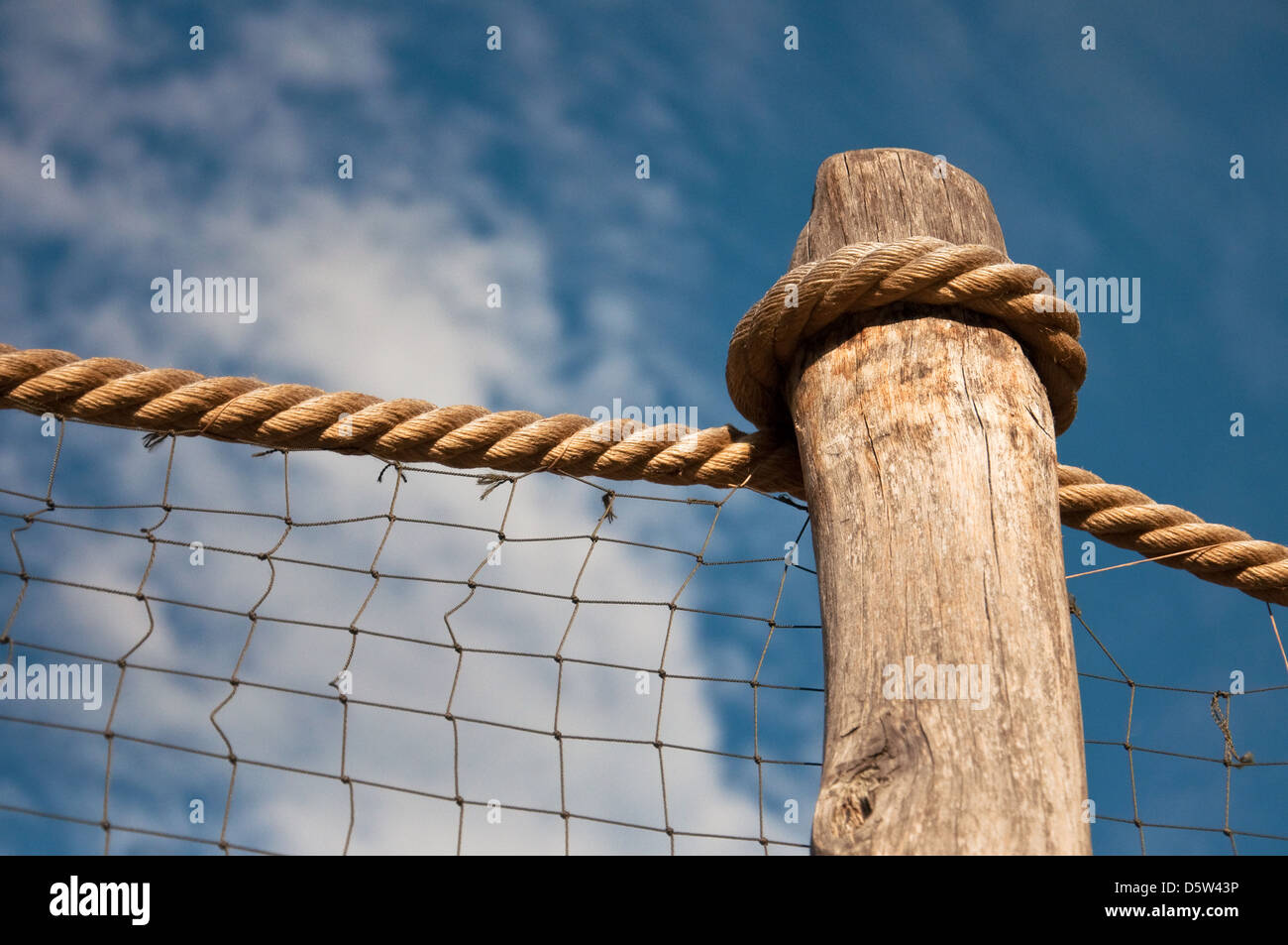 Versenden Sie Seil und Holzpfosten, gegen den blauen Himmel. Stockfoto