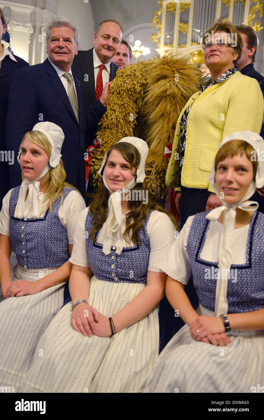 Der deutsche Bundespräsident Joachim Gauck (L-R), der Deutsche Bauernverband Verband (DBV) Joachim Rukwied und Präsident der deutschen Vereinigung der Frauen in Landwirtschaft Brigitte Scherb herumstehen einer Ernte Krone an Franzoesische Friedrichsstadtkirche in Berlin, Deutschland, 4. Oktober 2012. Frauen von der Younf Farmers' Association Wirmighausen Knien vor ihnen. A zuvor Pres Stockfoto