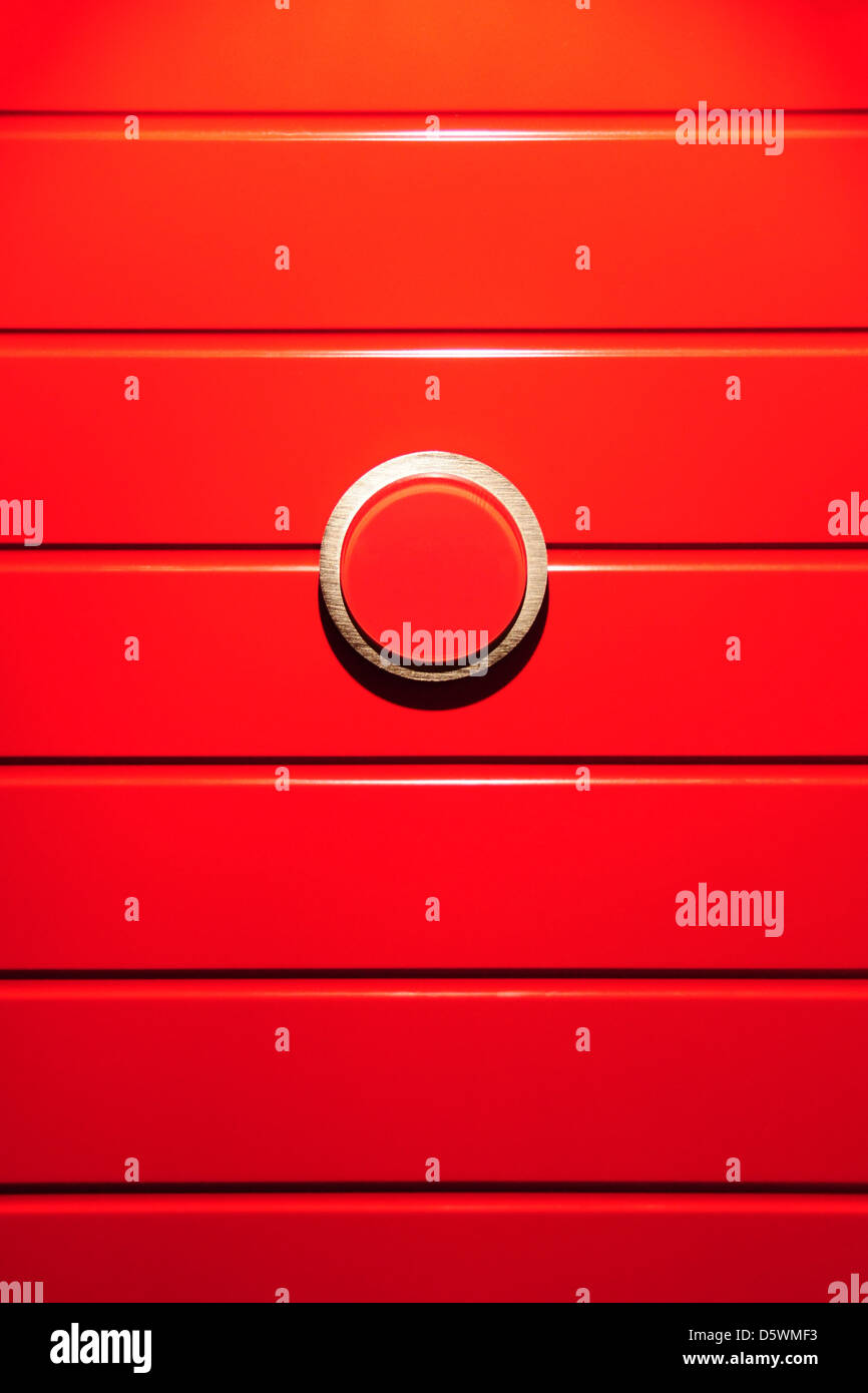 Detail einer rot bemalten Tür mit einem Edelstahlring. Stockfoto