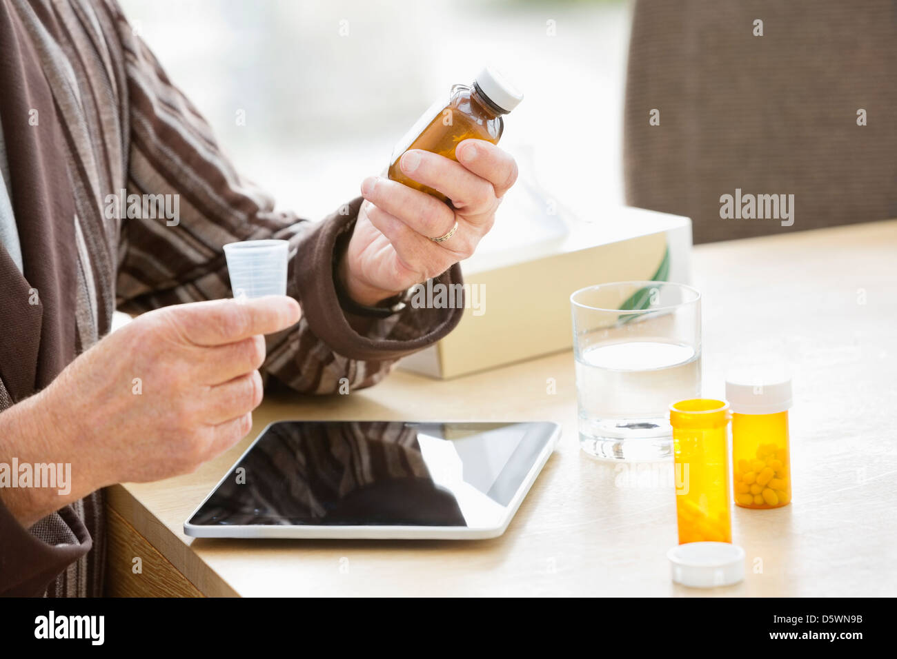 Älterer Mann, die Einnahme von Medikamenten am Tisch Stockfoto