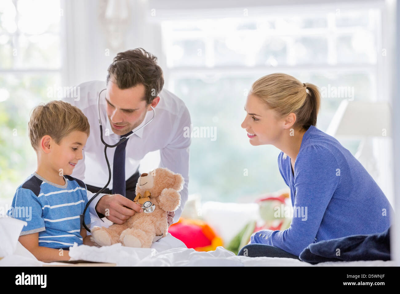 Arzt anhören Teddy Bär Herzschlag auf Hausbesuch Stockfoto