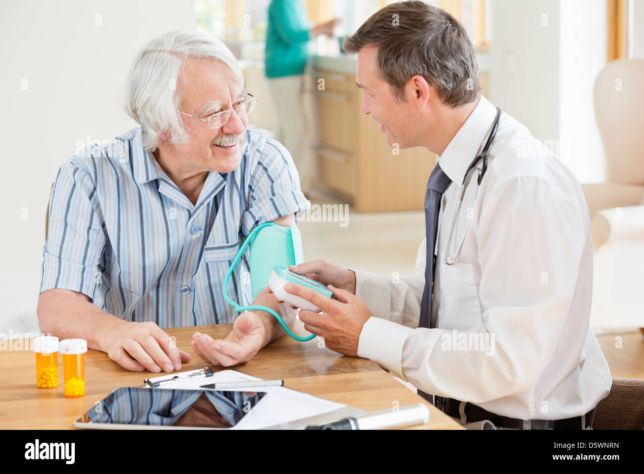 Arzt Tests älterer Patient Blutdruck bei Hausbesuch Stockfoto