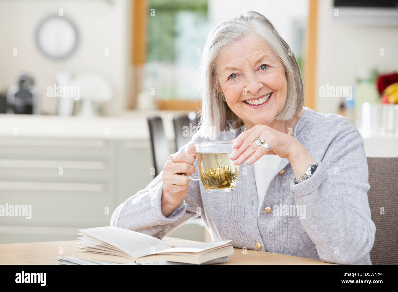 Ältere Frau Teetrinken und lesen Stockfoto