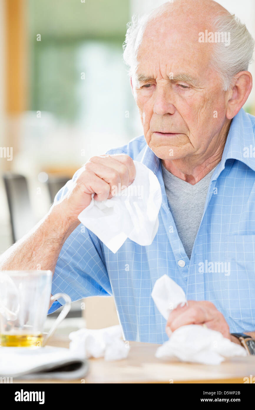 Älterer Mann mit kalten Nase abwischen Stockfoto