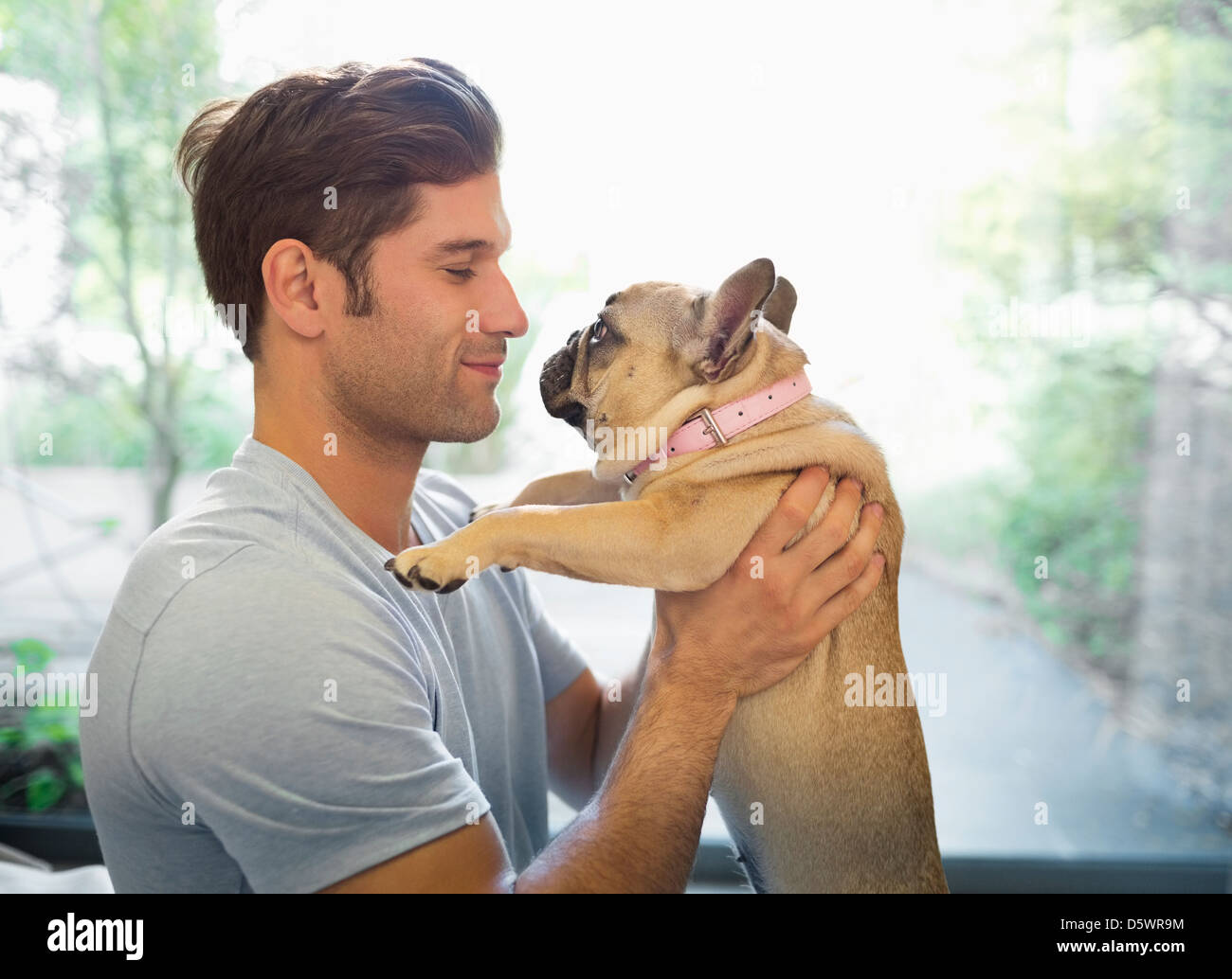 Lächelnd Mann halten Hund drinnen Stockfoto