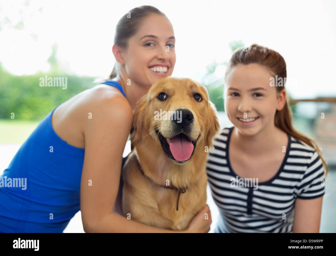 Mutter und Tochter lächelnd mit Hund Stockfoto