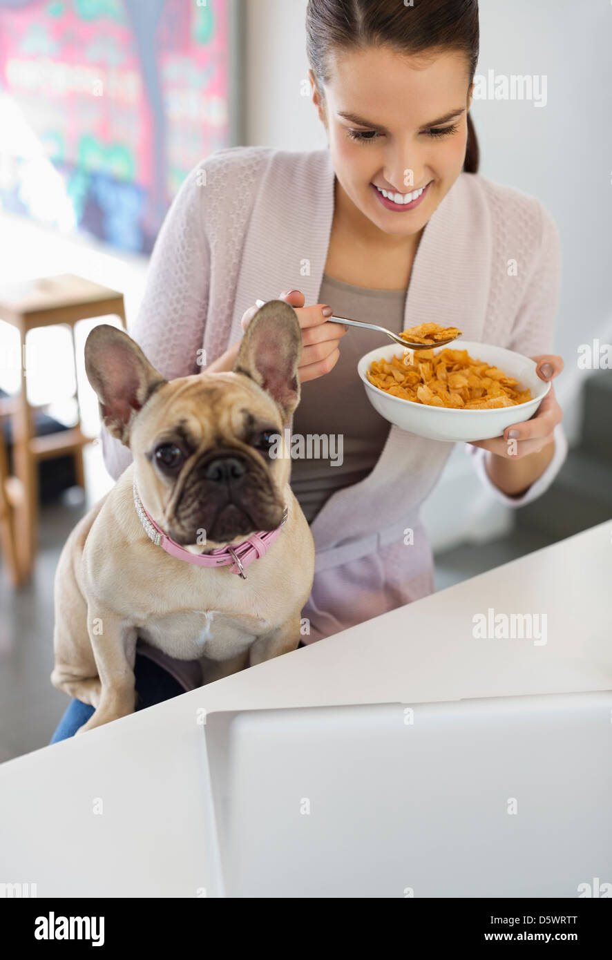 Frau essen Müsli mit Hund auf Schoß Stockfoto