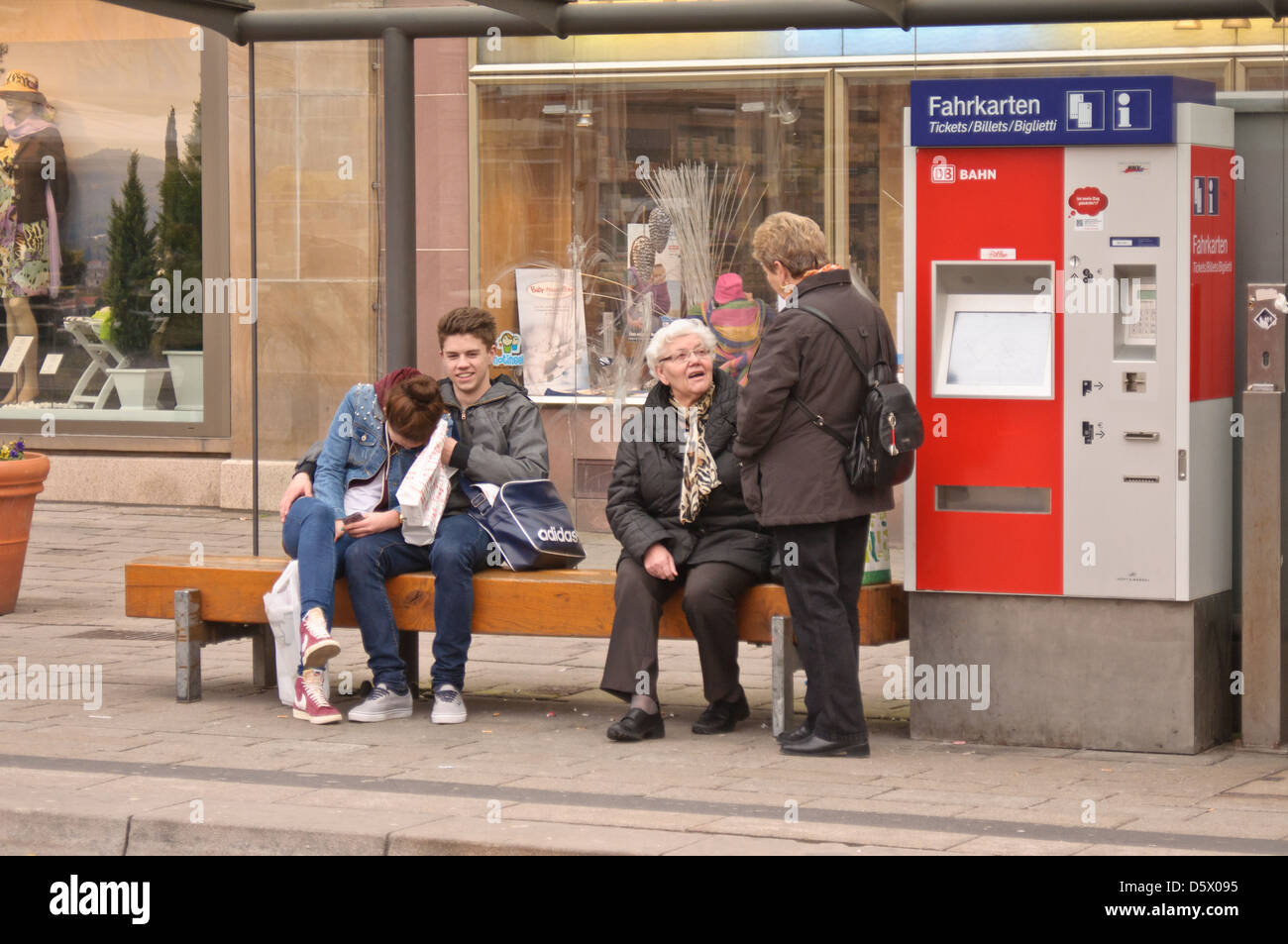 Jung und alt. Teenager Paar eine ältere Frauen warten an der  Bushaltestelle, Zwischenstation. Moderne Deutsche Bahn Ticket Automaten –  Heilbronn Deutschland Stockfotografie - Alamy