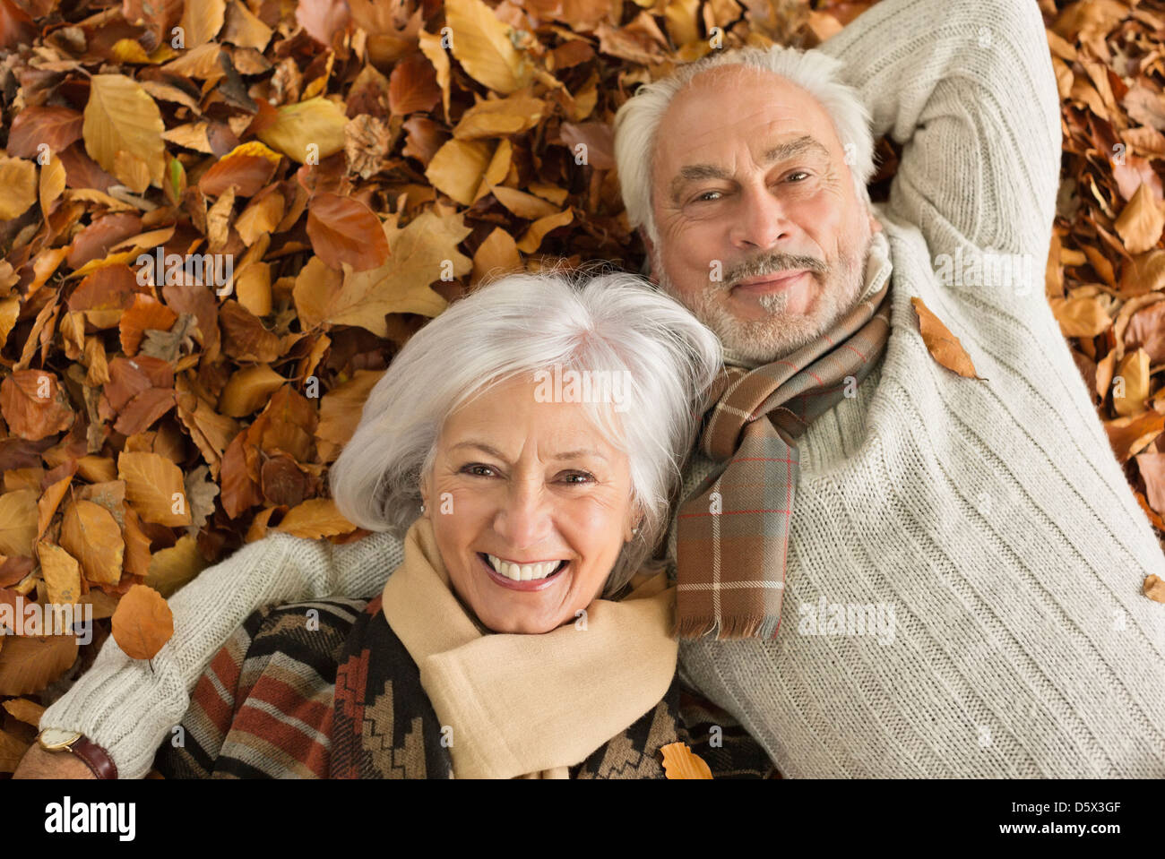 Älteres Ehepaar Verlegung im Herbstlaub Stockfoto