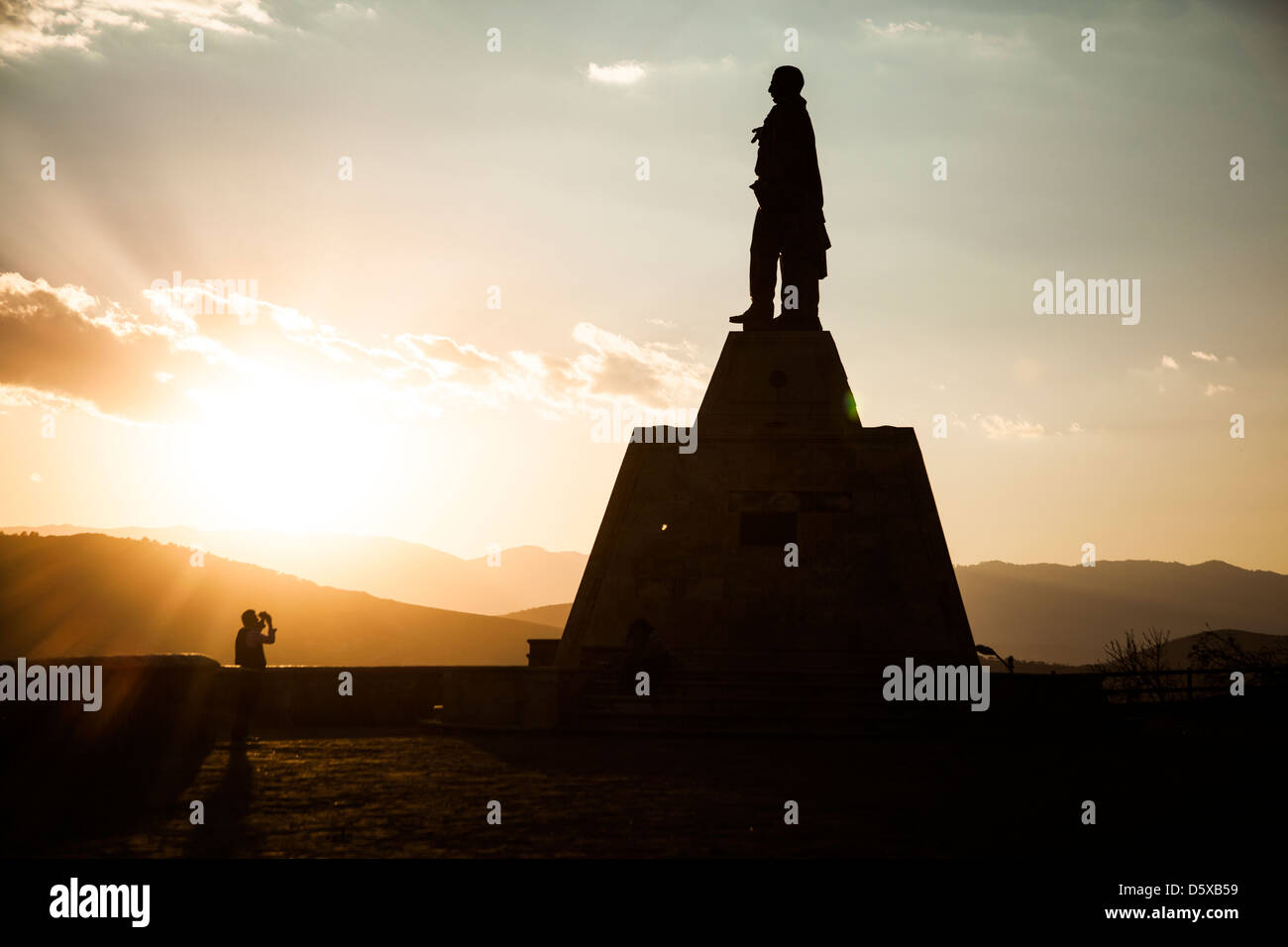 Bei Sonnenuntergang nimmt ein Mann ein Bild einer Statue von Benito Juarez, die Oaxaca-Stadt überblickt. Stockfoto