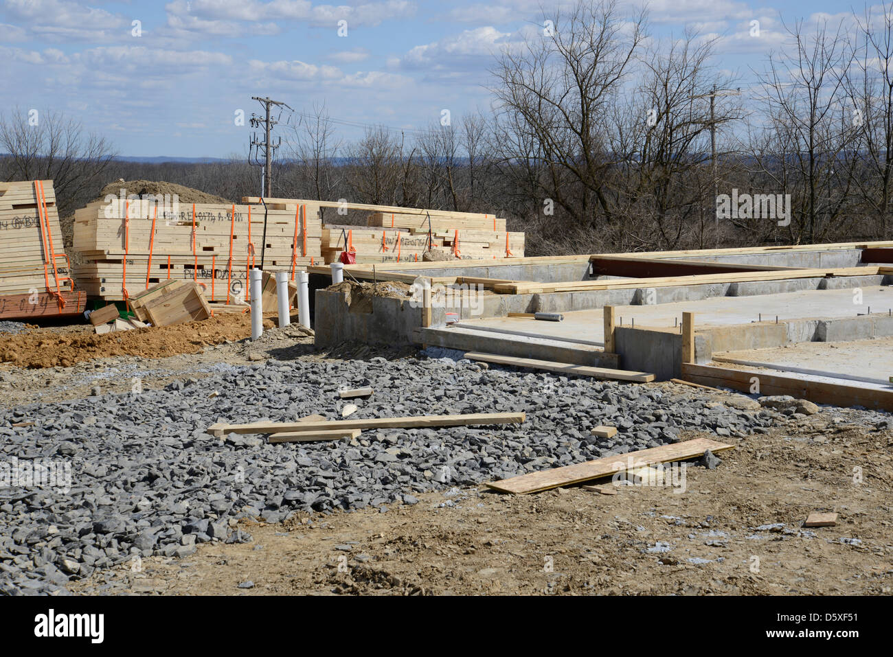 Haufenweise neue Bauholz durch ein Zement-Fundament für einen neuen Hauptaufbau. Stockfoto