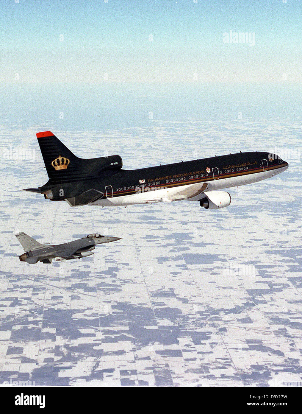 Ein F-16A Kampfflugzeug der Minnesota Air National Guard eskortiert Royal Jordanian 1 mit König Hussein I. über Minnesota, als er am 4. Februar 1999 nach Amman zurückkehrt. Die F-16A ist ein Mehrzweckjäger, der für Luft-Luft- und Luft-Boden-Missionen eingesetzt wird. Stockfoto