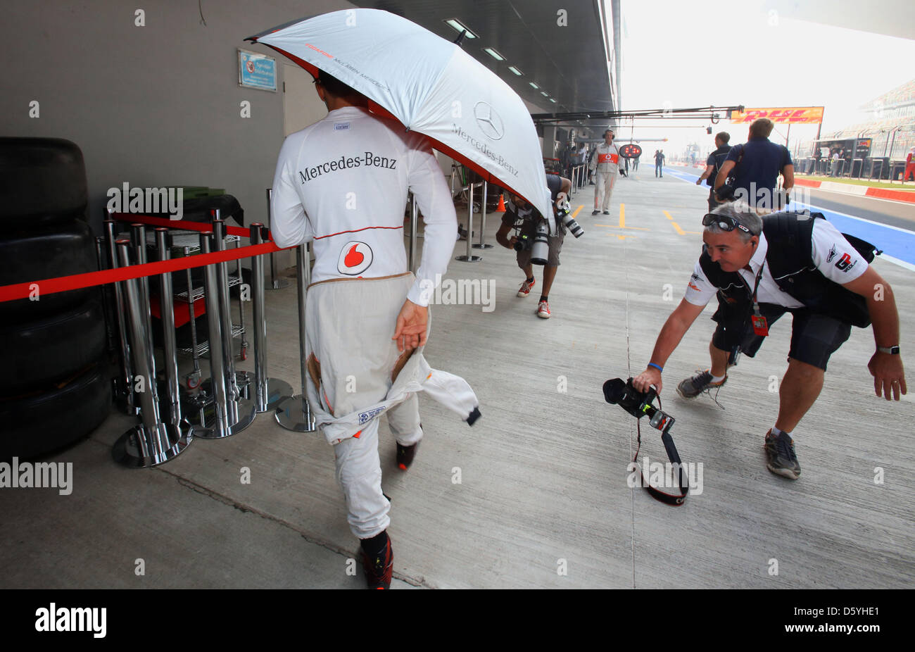 Britische Formel1-Fahrer Lewis Hamilton von McLaren Mercedes geht unter  einem Regenschirm durch die Boxengasse während das erste Training auf der  Rennstrecke Buddh International Circuit, Greater Noida, Indien, 26. Oktober  2012. Die Formel