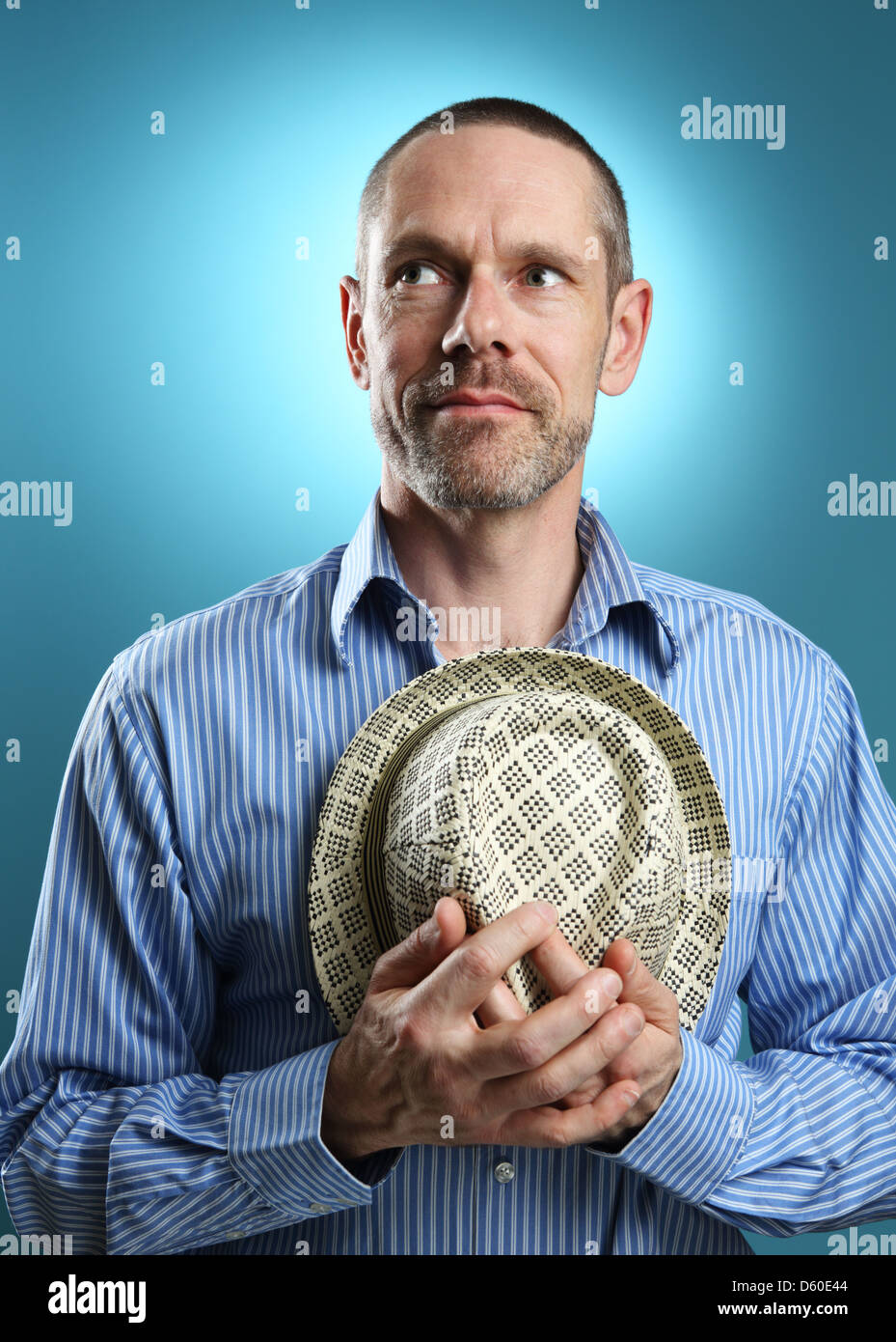 Porträt von einem reifen Erwachsenen halten eine Fedora und wegsehen von der Kamera mit einem sanften Lächeln. Stockfoto