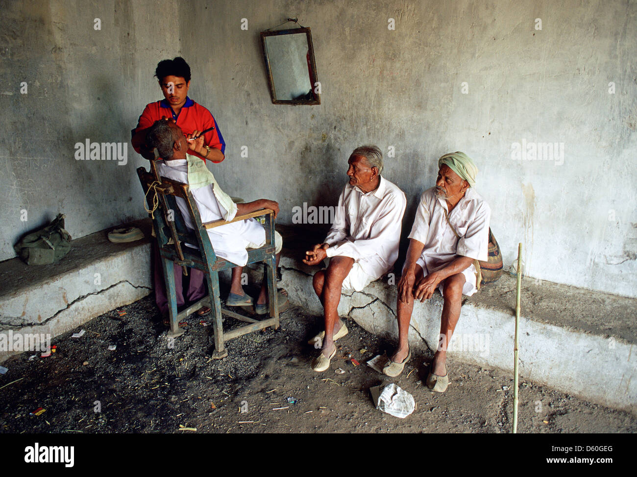 Ein Friseur mit seinen Kunden in einer abgelegenen Region. Sie gehören zum Stamm Bhil (Indien) Stockfoto
