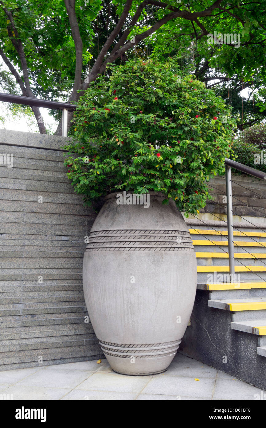 grüne Pflanze im Inneren große konkrete Vase auf der Stadtstraße Stockfoto