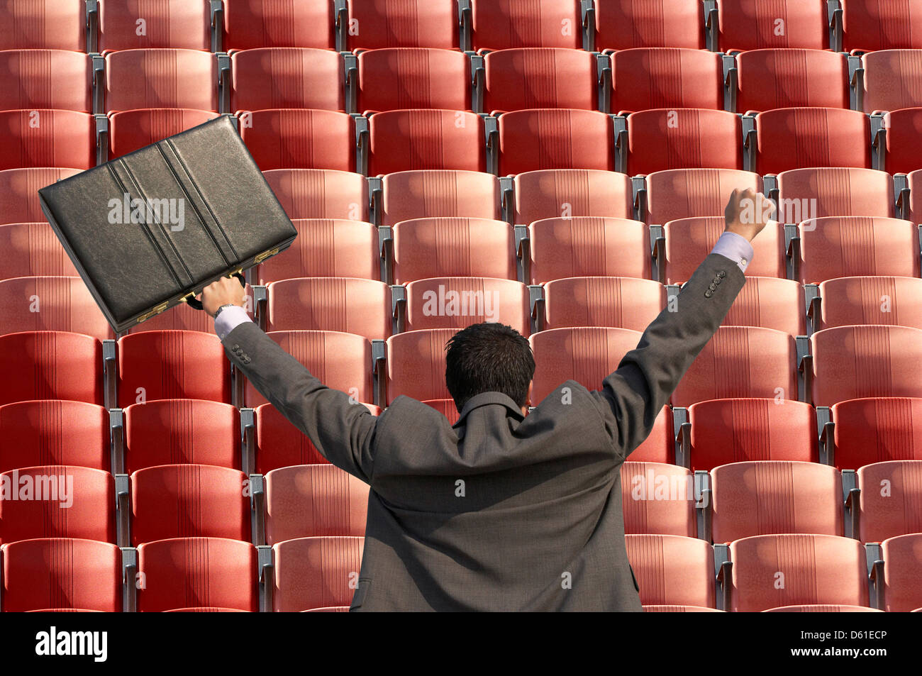 Rückansicht des siegreichen Geschäftsmann mit Aktenkoffer mit Blick auf Zeilen mit roten sitzen t Stadion Stockfoto
