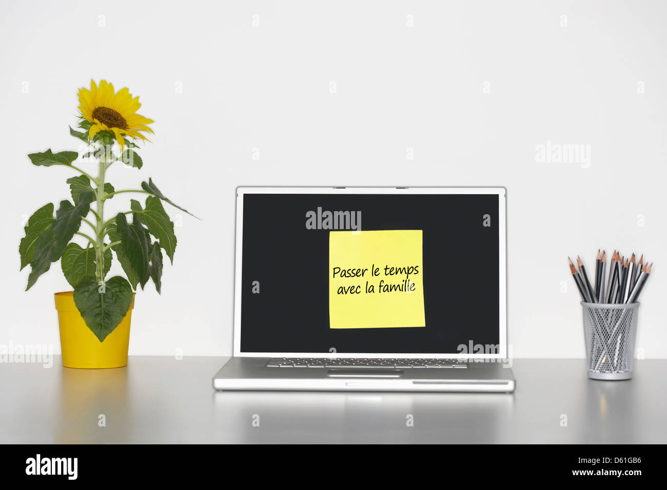Sonnenblumen Pflanze Schreibtisch klebrig Briefpapier französische Laptop-Bildschirm sagen "Passer le Temps Vec la Famille" Stockfoto