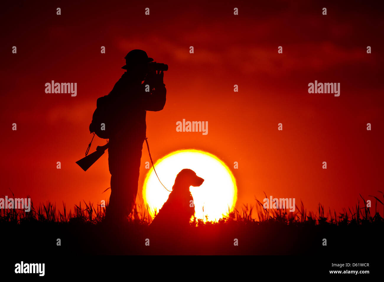 ILLUSTRATION - Hunter Lars Heinrich und sein Hund Canto stehen vor der aufgehenden Sonne in Alt Madlitz, Deutschland, 2. Mai 2012. Dieses Wochenende Brandenburg feiert seinen Jäger Tag. Foto: Patrick Pleul Stockfoto