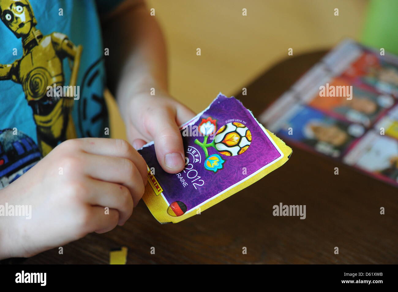 Ein Junge öffnet ein Panini-Sticker-Paket und stellt sie in seiner offiziellen Stickeralbum die Panini UEFA European Football Championships 2012 in Polen und der Ukraine in Berlin, Deutschland, 2. Mai 2012. Foto: Jens Kalaene Stockfoto