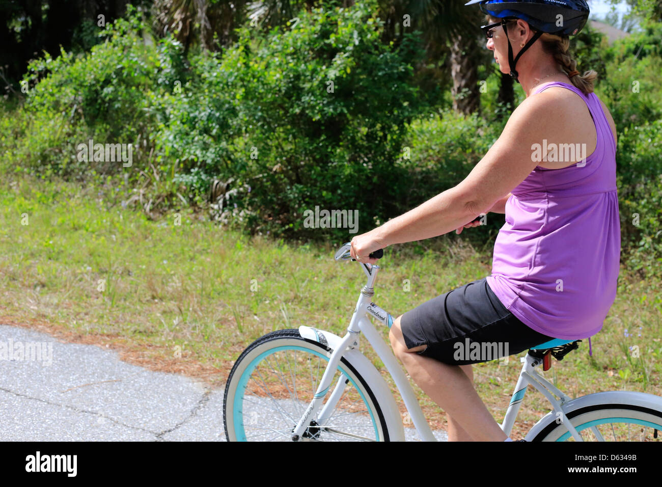 Einer mittleren Alters oder ältere Frau, die mit dem Fahrrad auf einem Vorort Straße in den USA Stockfoto