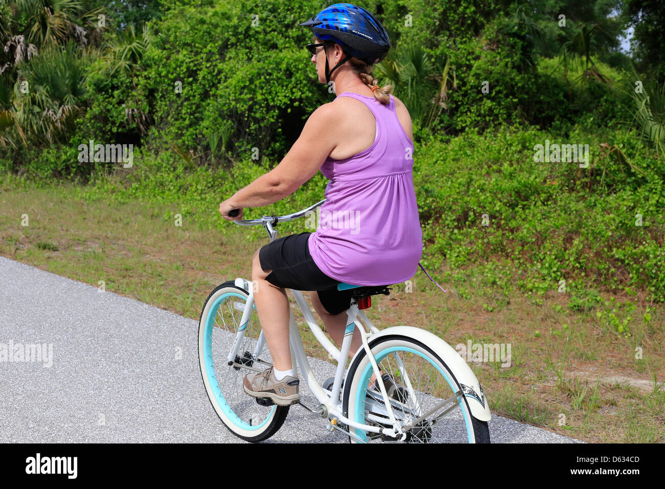 Einer mittleren Alters oder ältere Frau, die mit dem Fahrrad auf einem Vorort Straße in den USA Stockfoto