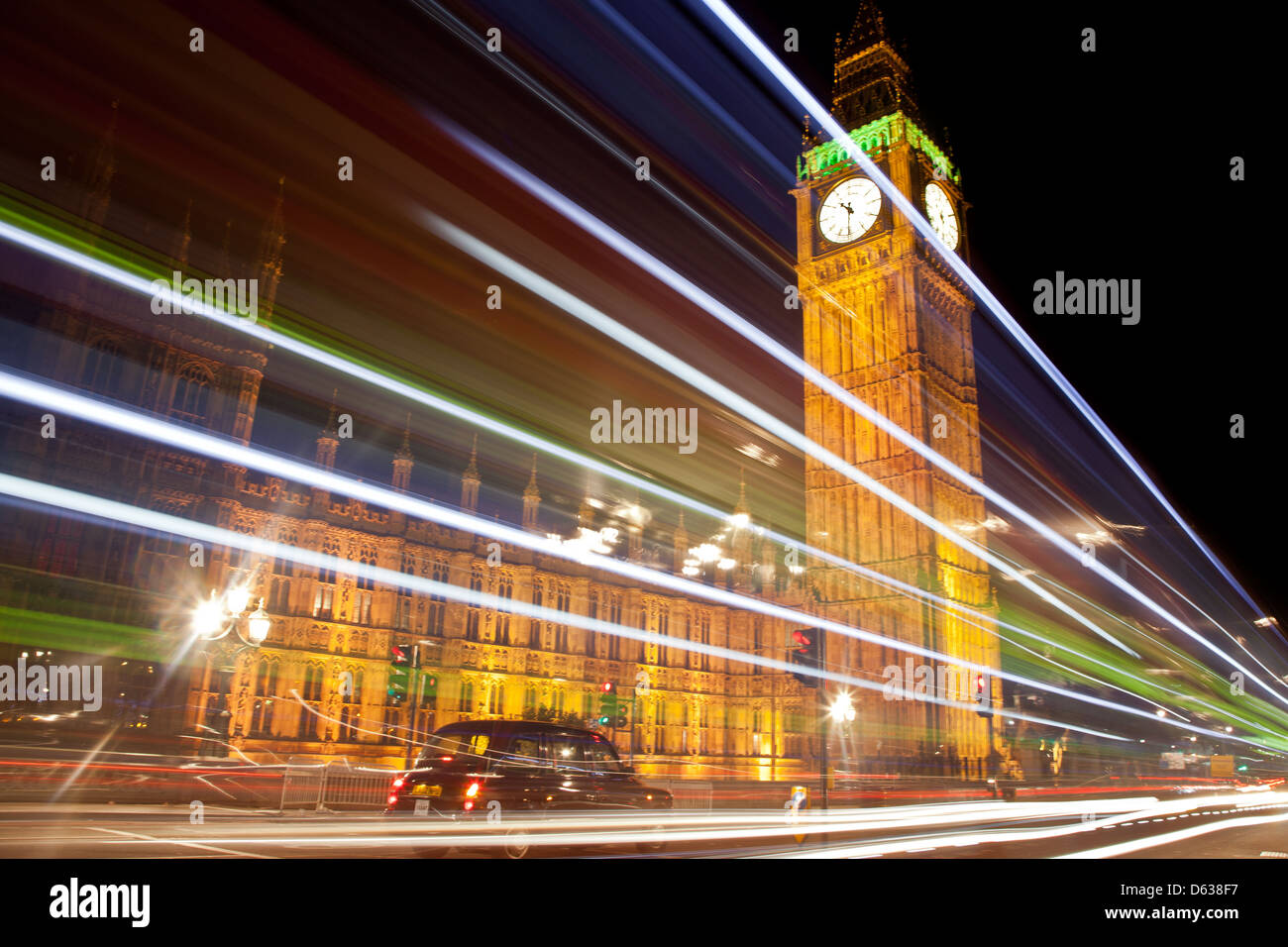 Eine nächtliche Szene zeigt ein Taxi von Big Ben clock, während helle Streifen von einem vorbeifahrenden Bus, durch eine Langzeitbelichtung Wirkung getan werden Stockfoto